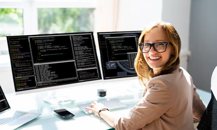 Lady sitting at computer looking at code.